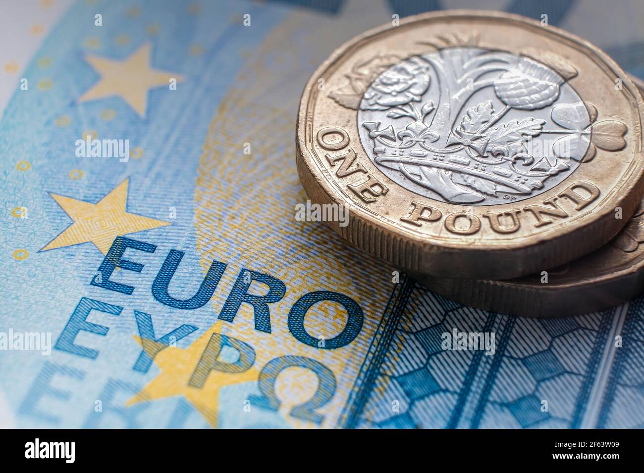 Moneta inglese da una libbra posta sulla banconota DA 20 EURO con le parole visibili "EURO" tradotte in diverse lingue. Concetto. Messa a fuoco selettiva. Macro. Foto Stock