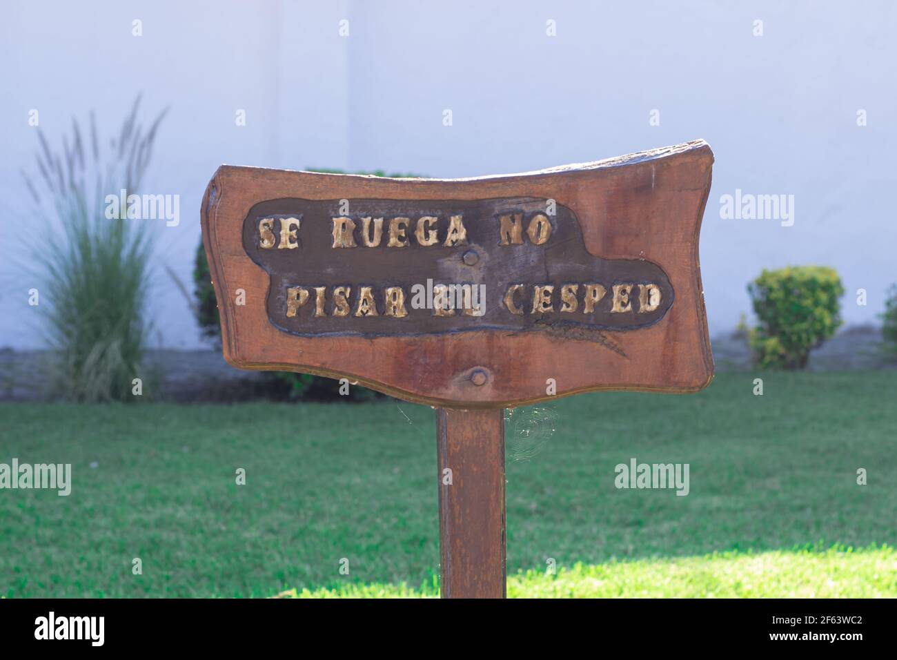 Cartello in legno in spagnolo: Si prega di non salire sull'erba. Foto Stock