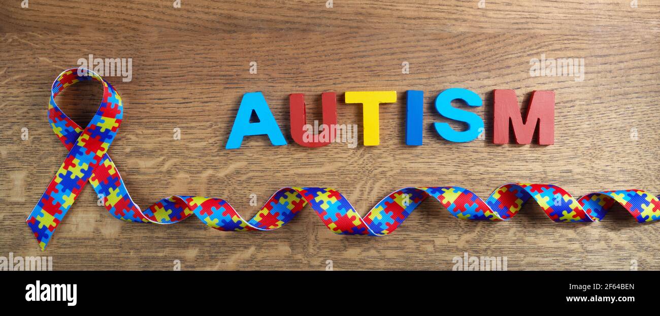 L'autismo mondiale premia giorno. Nastro di motivo di puzzle su sfondo di legno Foto Stock