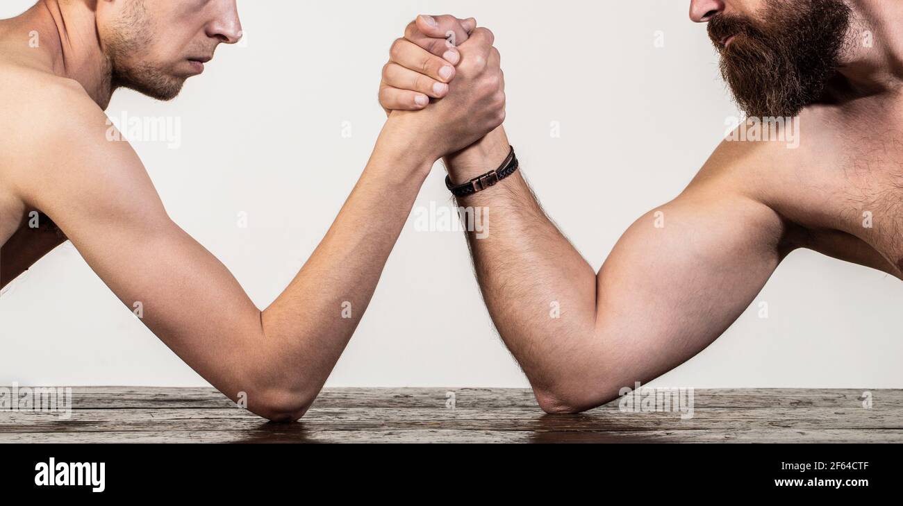 Due mani di uomo hanno stretto il braccio wrestling, forte e debole, corrispondenza disuguale. Braccio uomo pesante muscled bearded wrestling un uomo debole puny. Bracci di lotta sottili Foto Stock