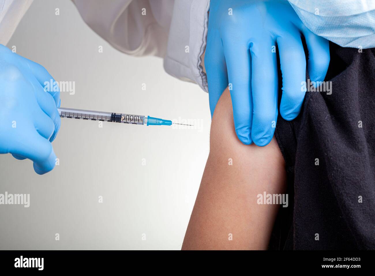 Un operatore sanitario che indossa guanti e camice bianco sta somministrando un vaccino infantile a un bambino caucasico. Immagine concettuale di primo piano per il vacc bambino Foto Stock