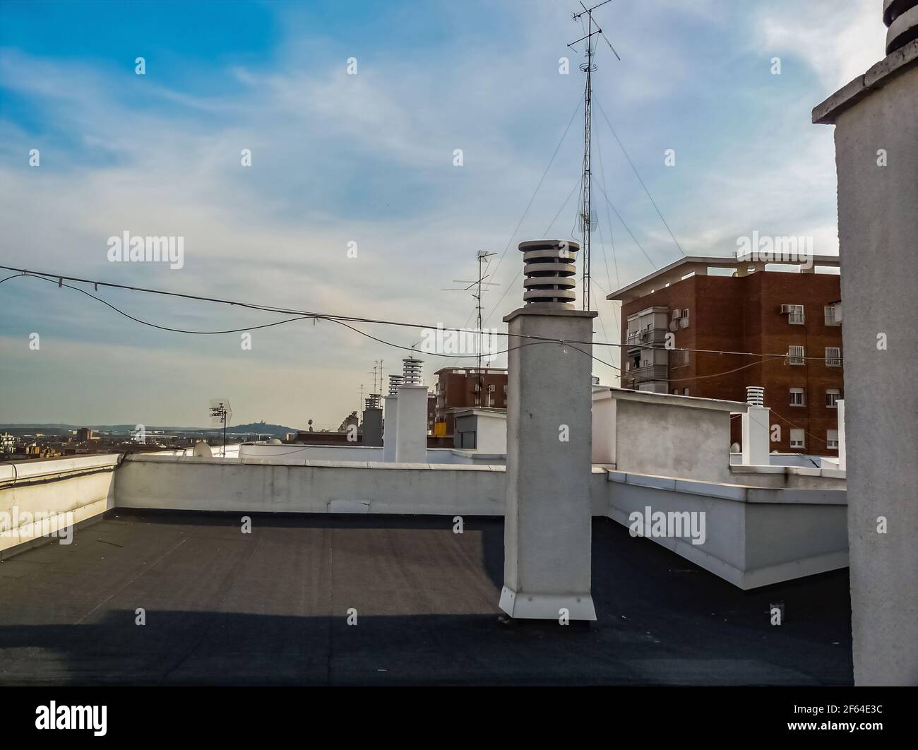 Vista sulla città con un cielo estivo blu. Vista dal tetto, con molti camini e antenne. Foto Stock