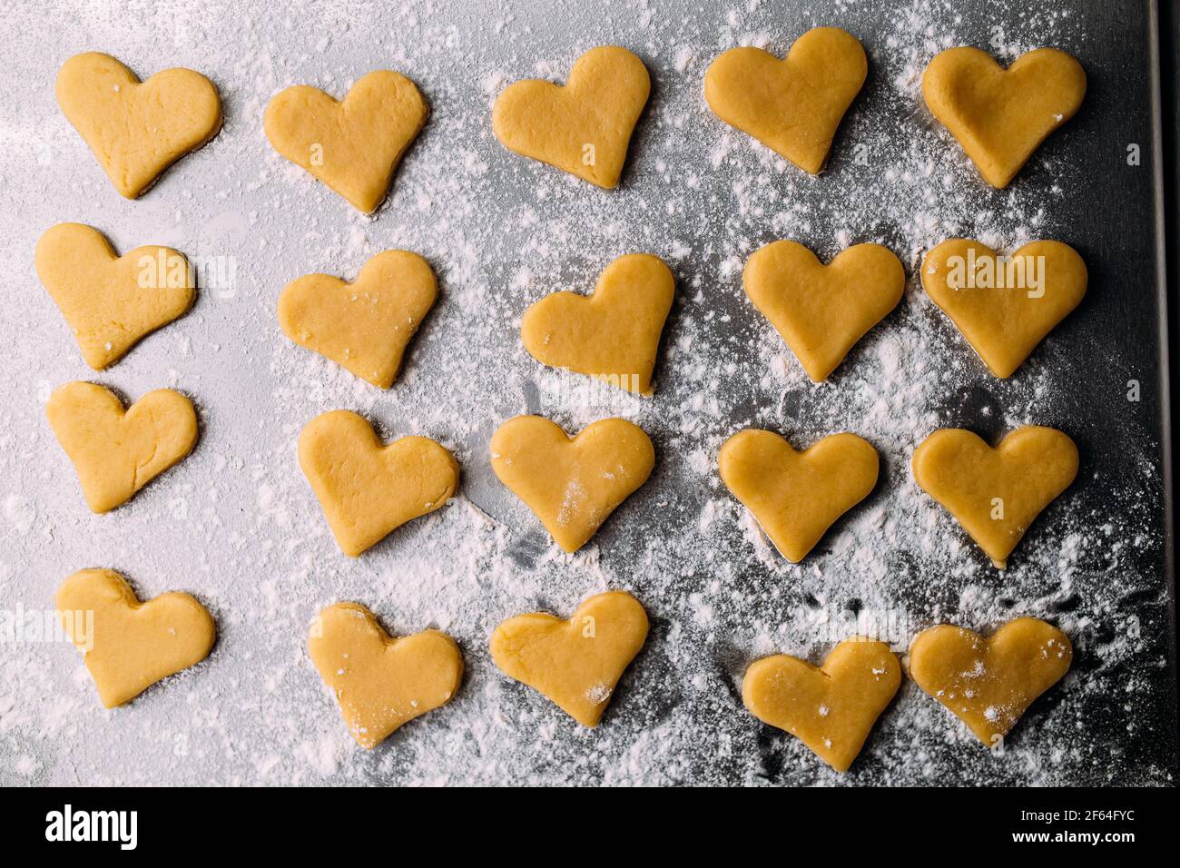 Biscotti semifiniti a forma di cuore con farina Foto Stock
