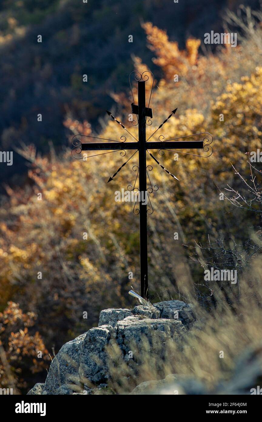 silhouette di crocifisso in ferro posto sul fianco della montagna illuminato in controluce. Abruzzo, italia, europa Foto Stock