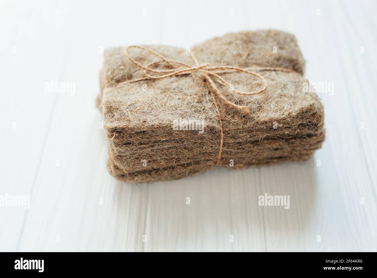 Confezioni di tappetini in lino su sfondo bianco di legno. Micrgreens che piantano business. Base naturale per piante crescenti. Vitamine dalla natura. Vegan e. Foto Stock