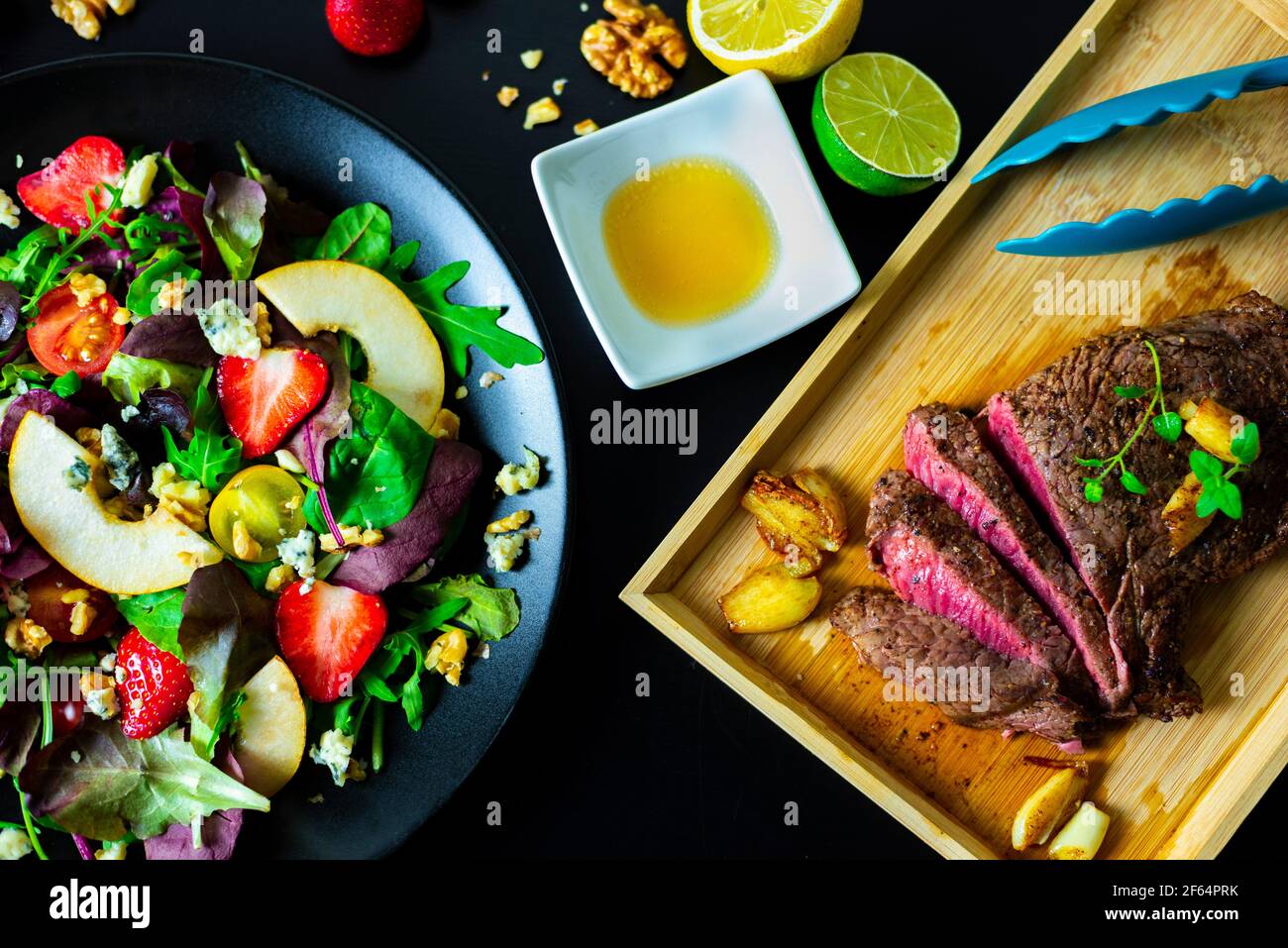 Bistecca tagliata con insalata mista con fragole, pere, noci, formaggio blu e salsa al miele di limone Foto Stock