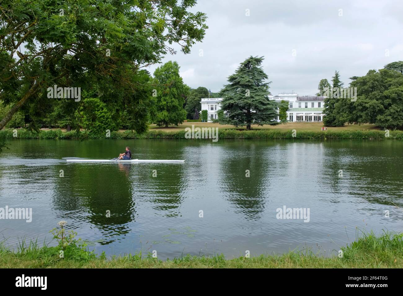 Un uomo scolpisce oltre la Henley Business School sul fiume Tamigi, vicino a Henley-on-Thames, Oxfordshire, Regno Unito Foto Stock