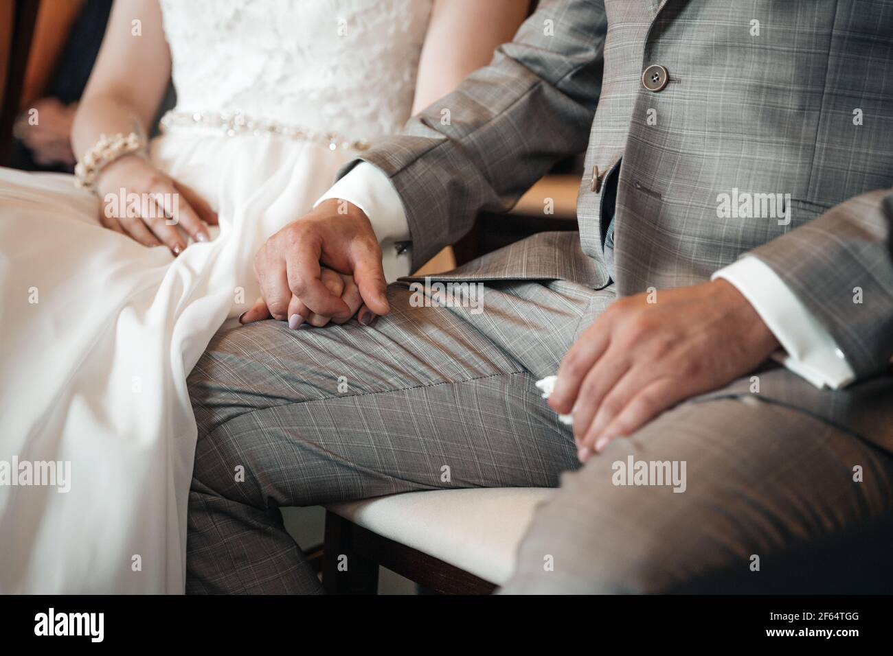 Sposo e sposa che tengono le mani durante la cerimonia nuziale Foto Stock
