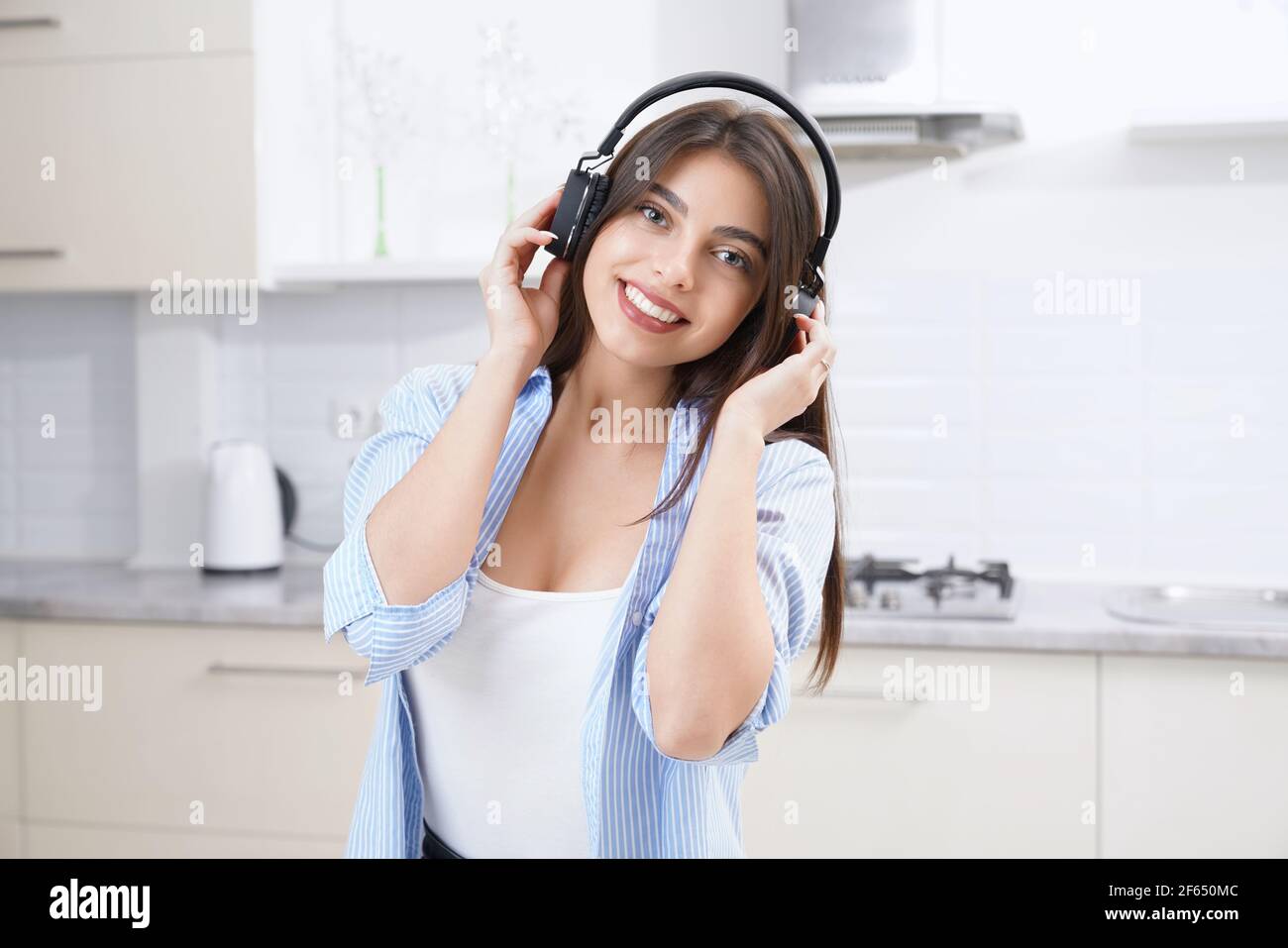 Primo piano di una donna bruna sorridente che ascolta musin nelle cuffie. Concetto di tempo libero a casa. Foto Stock