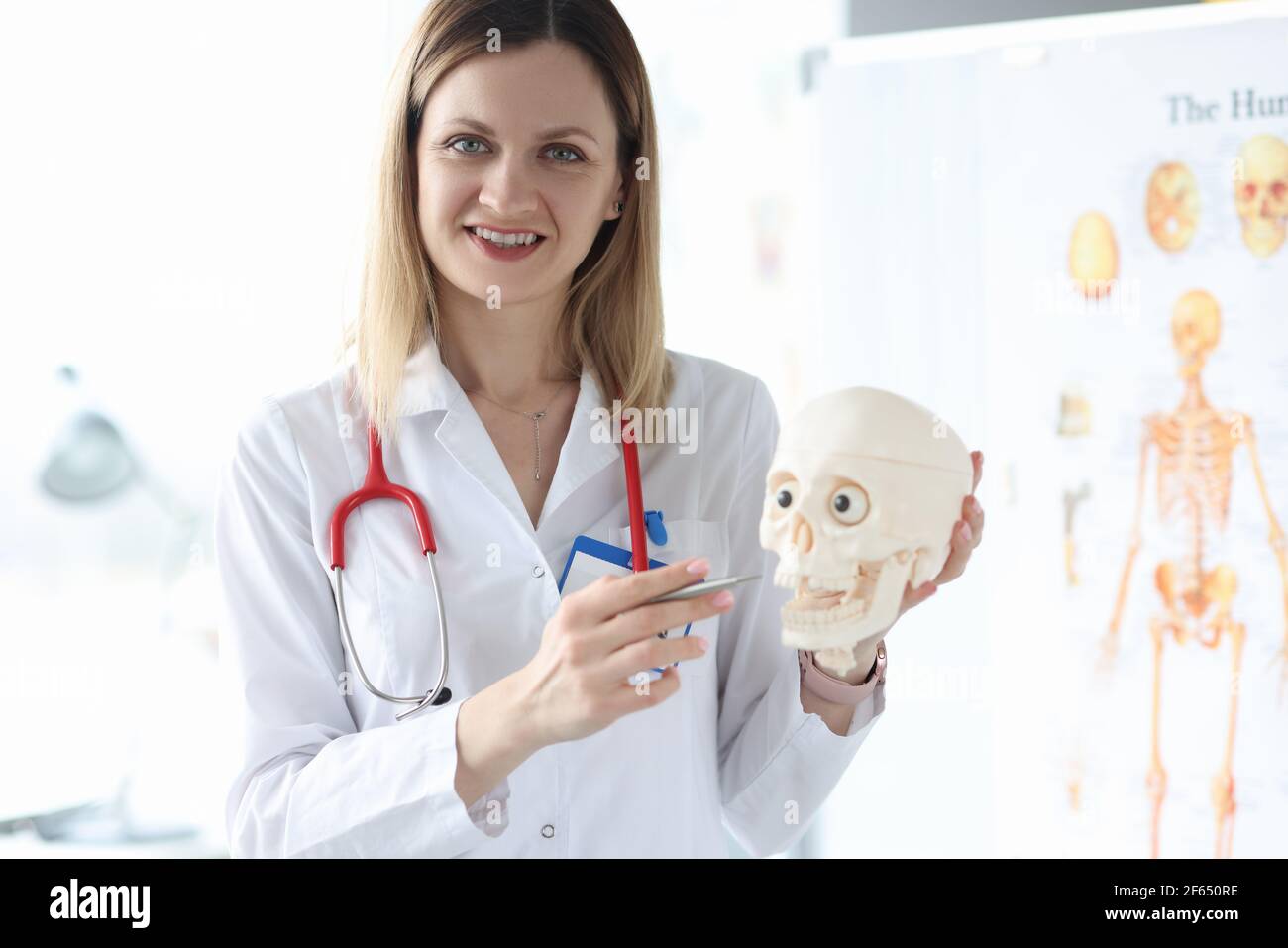 Un medico ritratto sorridente tiene il primo piano del cranio umano Foto Stock