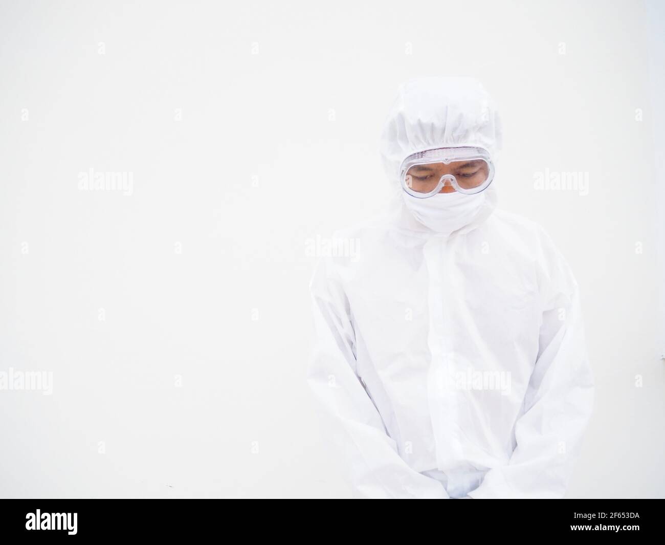 Medico o scienziato asiatico maschile in uniforme DPI suite con indossare maschera protettiva. L'umore è come triste e calmo, coronavirus o COVID-19 concetto Foto Stock
