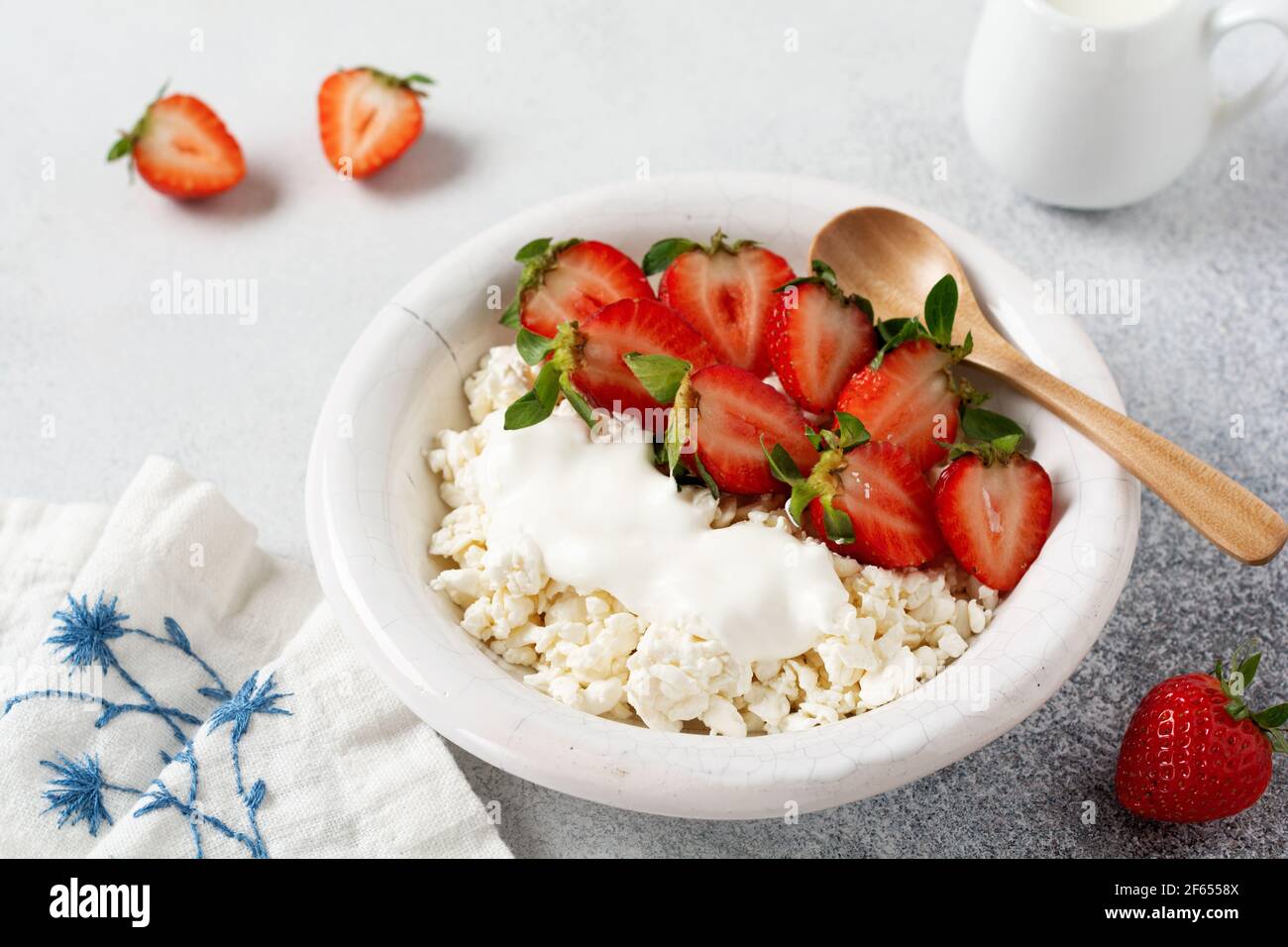 Formaggio di cottage, formaggio di cagliata con fragole in una ciotola, prodotto caseario artigianale di produzione agrana. Prodotto caseario sano ricco di calcio e proteine. Foto Stock