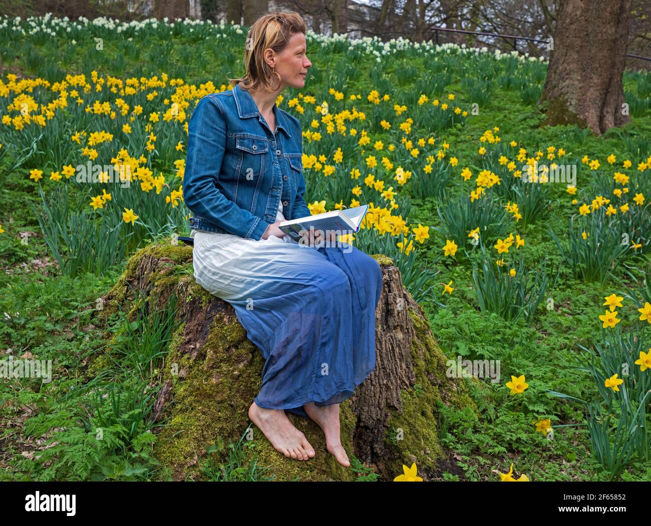 Edimburgo, Scozia, Regno Unito. 30 marzo 2021. Nuvoloso nel bosco, temperatura 15 gradi centigradi. Anna Neubert-Wood di WanderWomen Scozia gode della pace e della solitudine rilassarsi tra i narcisi dorati. Anna ama condividere la sua passione per gli spazi aperti con le donne che hanno la stessa mentalità: Per fare escursioni in luoghi bellissimi con tutto ciò di cui ha bisogno nello zaino, vagare e trovare meraviglia nella natura, essere Uniti con ciò che circonda lei e i suoi compagni. Foto Stock