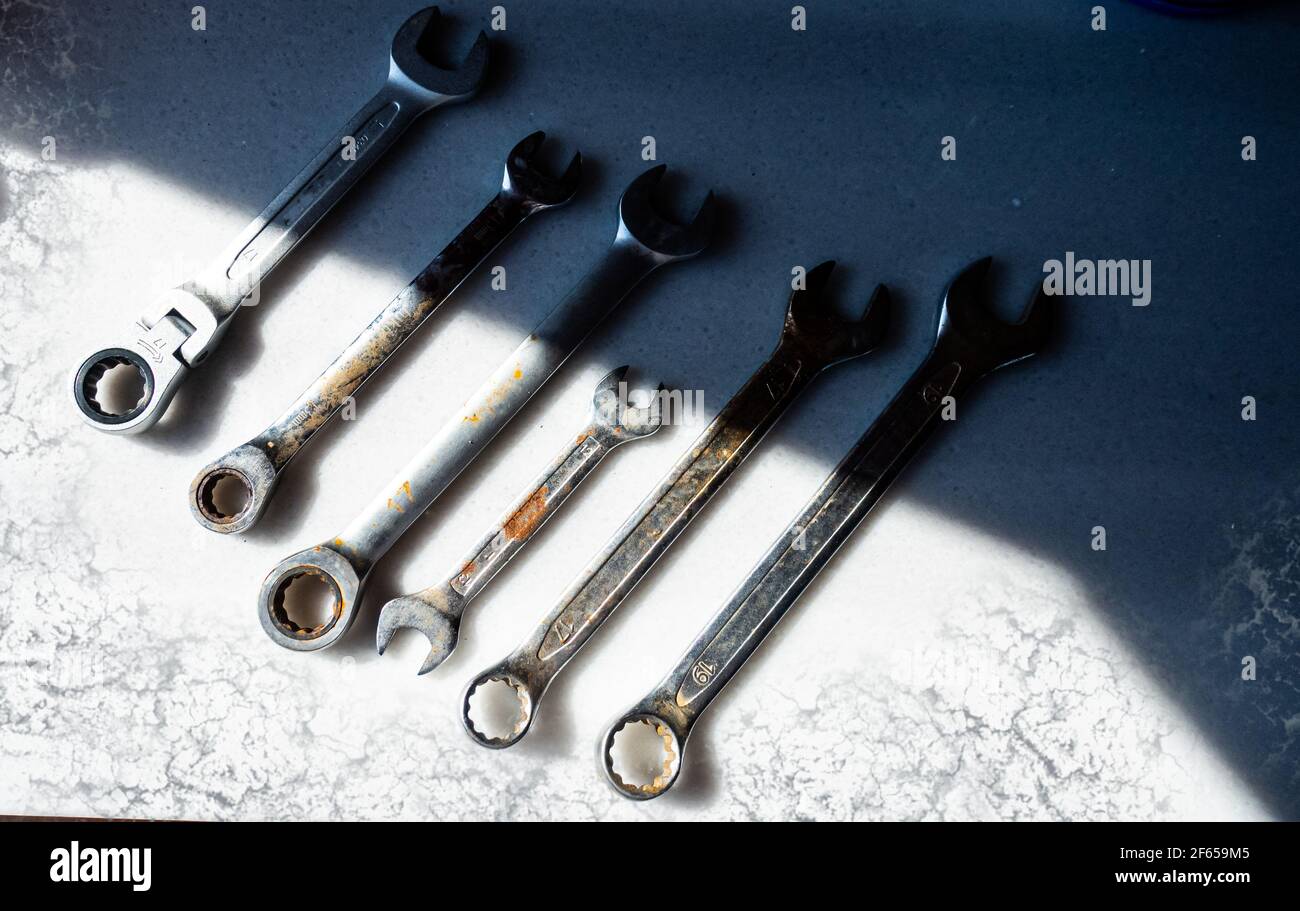 Vecchi e arrugginiti utensili per chiavi sul piano di lavoro bianco Foto Stock