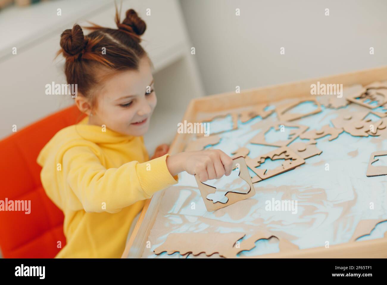 Bambina che gioca con il giocattolo a forma di sabbia. Formazione in età precoce. Concetto di psicologia cognitiva dei bambini piccoli Foto Stock