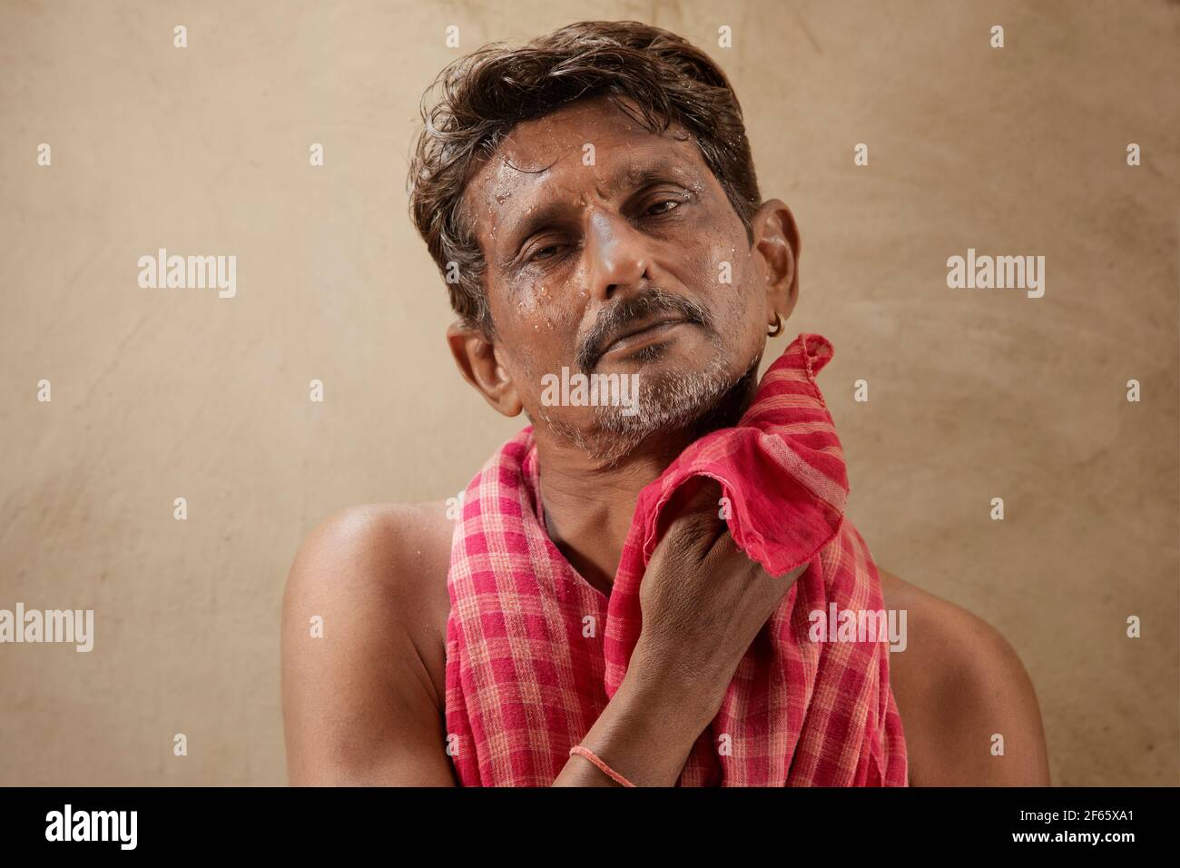 Un contadino strofinando il sudore con un panno rosso Foto Stock