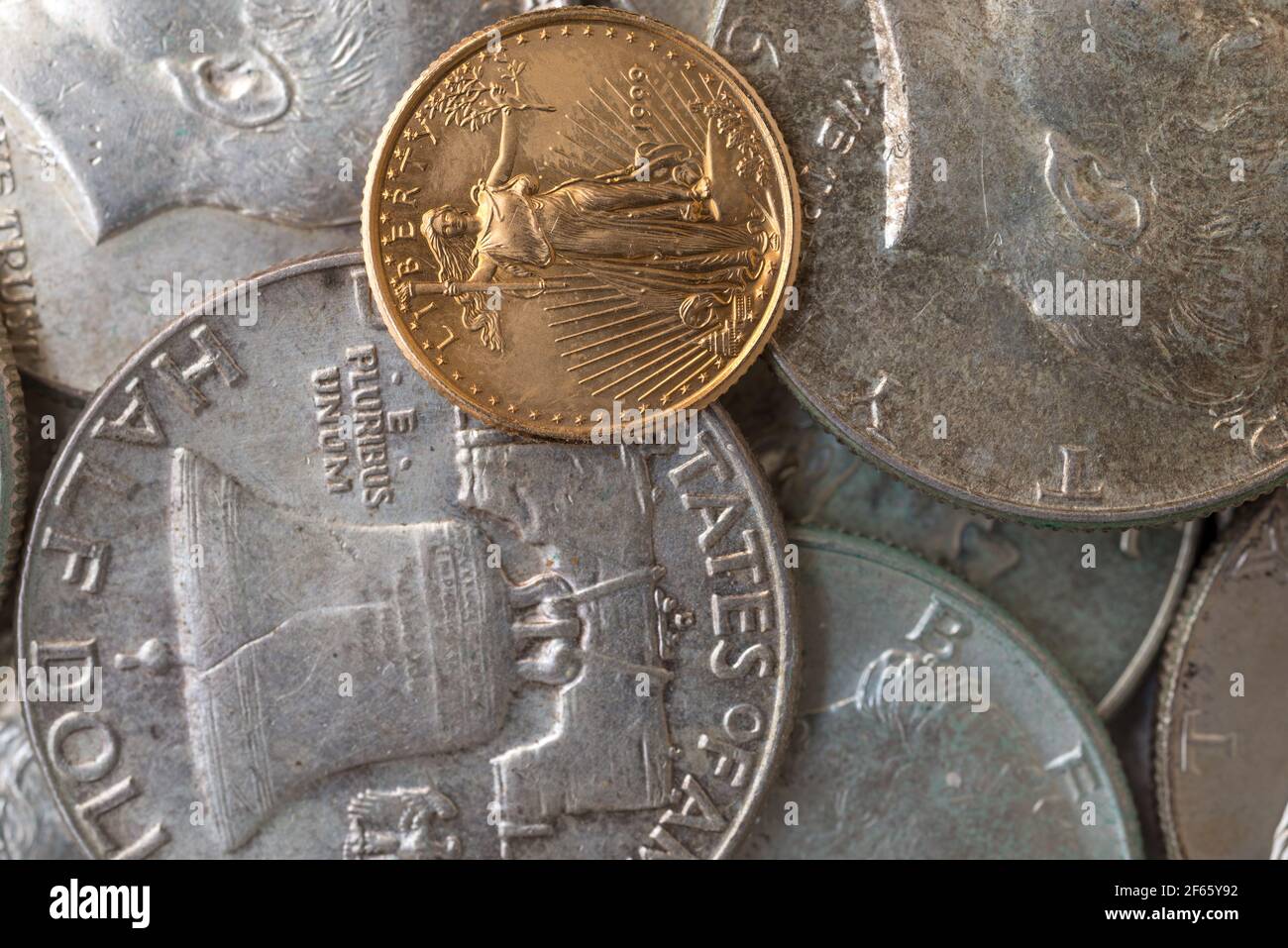 Vista molto ravvicinata di Kennedy e Franklin monete d'argento mezzo dollaro con una piccola libertà d'oro. Foto Stock