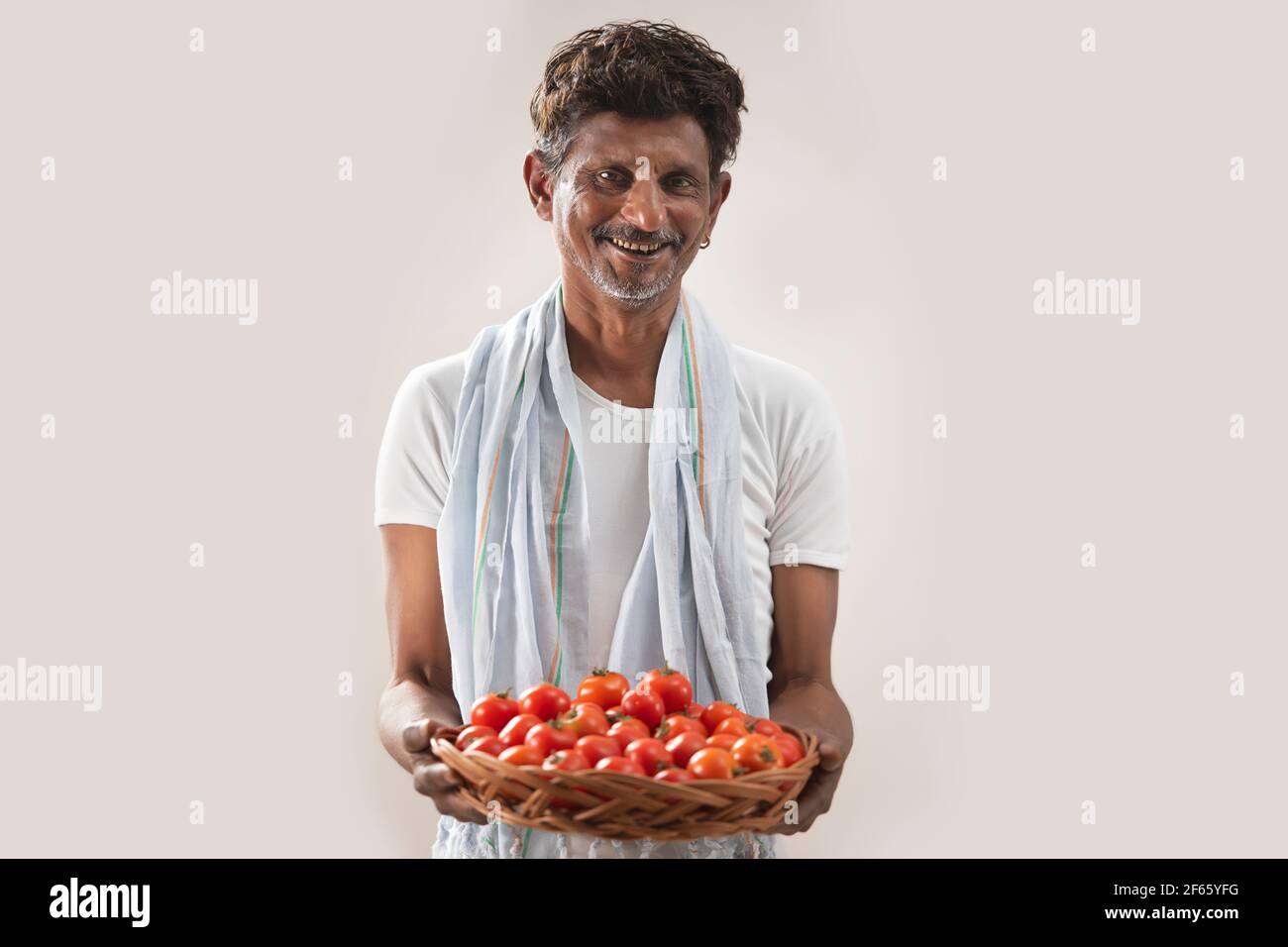 Coltivatore indiano che tiene cestino con pomodori Foto Stock