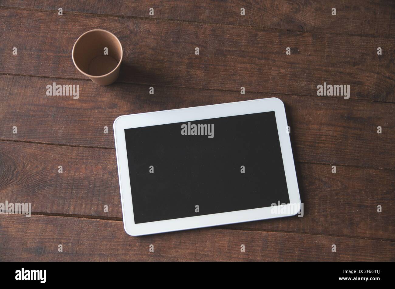 Moderno spazio di lavoro per ufficio con tablet pc sul tavolo e una tazza di caffè usa e getta. Per una presentazione o un portfolio di progetti. Foto Stock