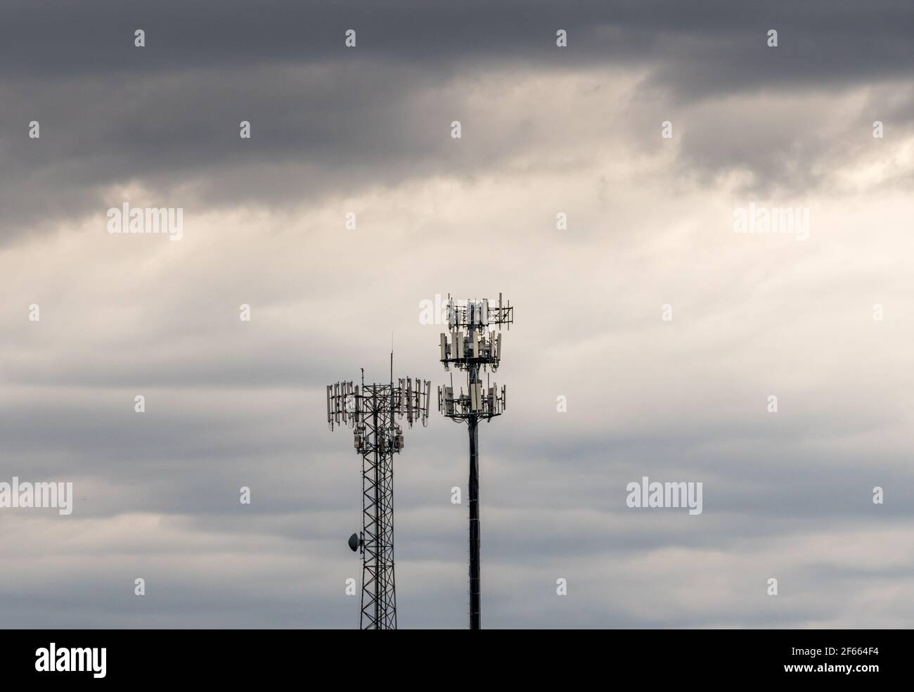 Due torri che forniscono banda larga cellulare e servizio dati per le aree rurali in un giorno di tempesta. Illustra il digital divide. Foto Stock