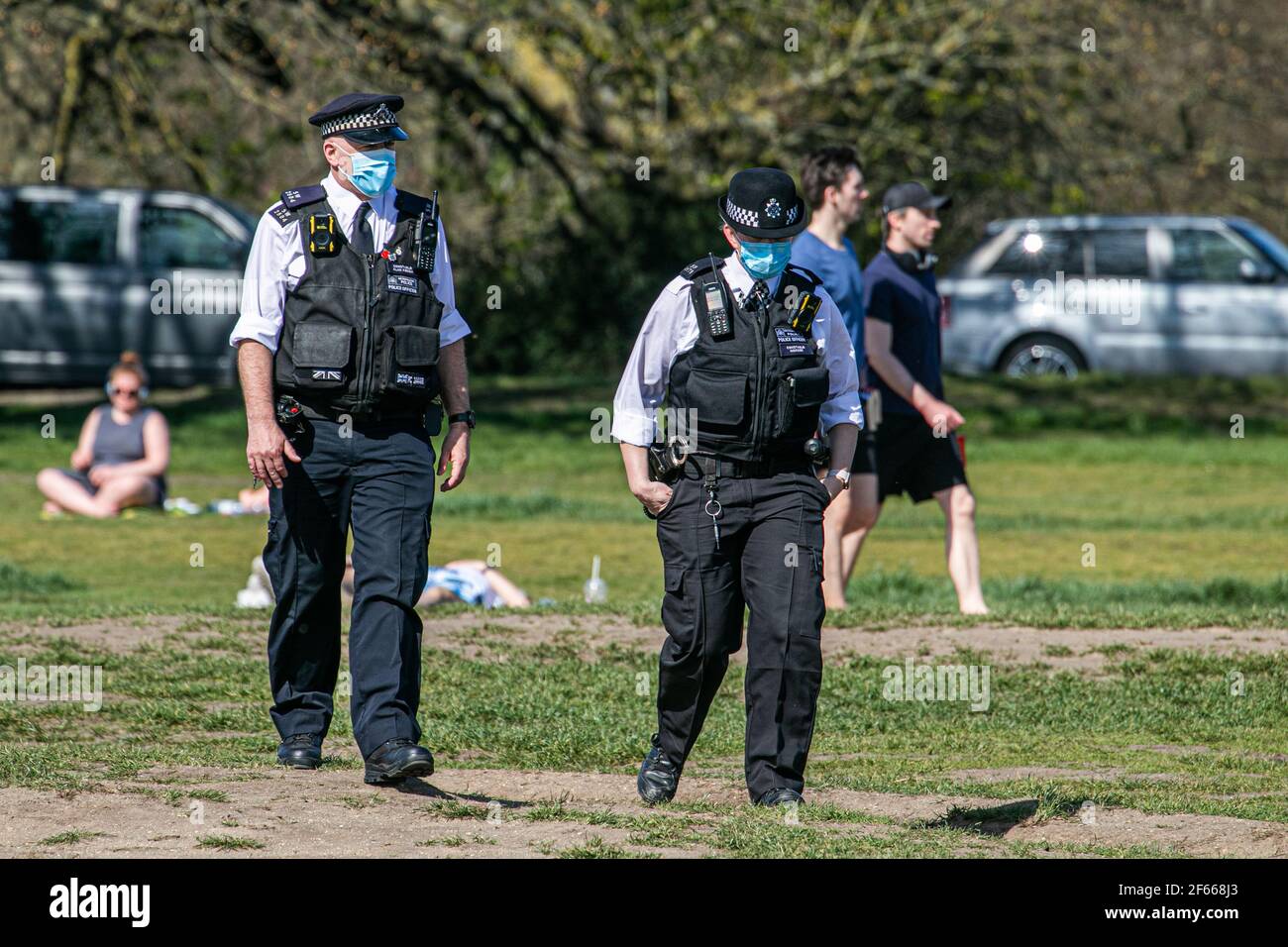 WIMBLEDON LONDRA, REGNO UNITO 30 MARZO 2021. Gli agenti di polizia camminano tra le folle, mentre il caldo sole primaverile ha incoraggiato persone e amici a incontrarsi all'aperto su Wimbledon Common un giorno dopo che le restrizioni di blocco sono state attenuate consentendo a un massimo di sei persone di incontrarsi all'aperto. Credit amer Ghazzal/Alamy Live News Foto Stock