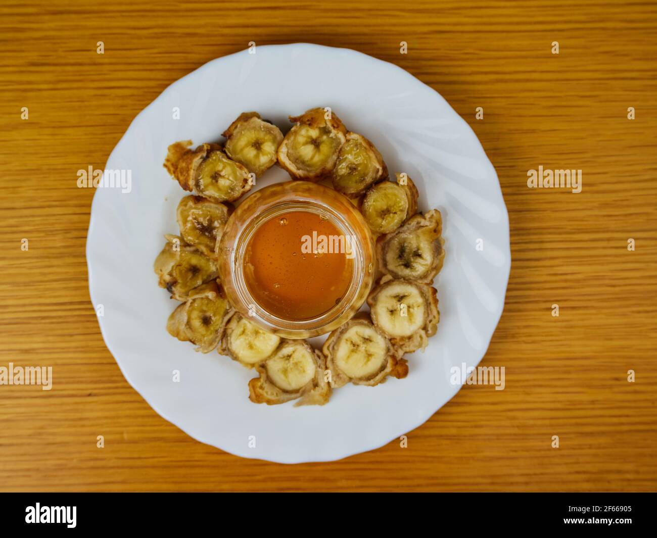 Fette fritte della pianta matura e un bicchiere di miele che fa un alveare su un piatto rotondo di legno. Vista dall'alto Foto Stock