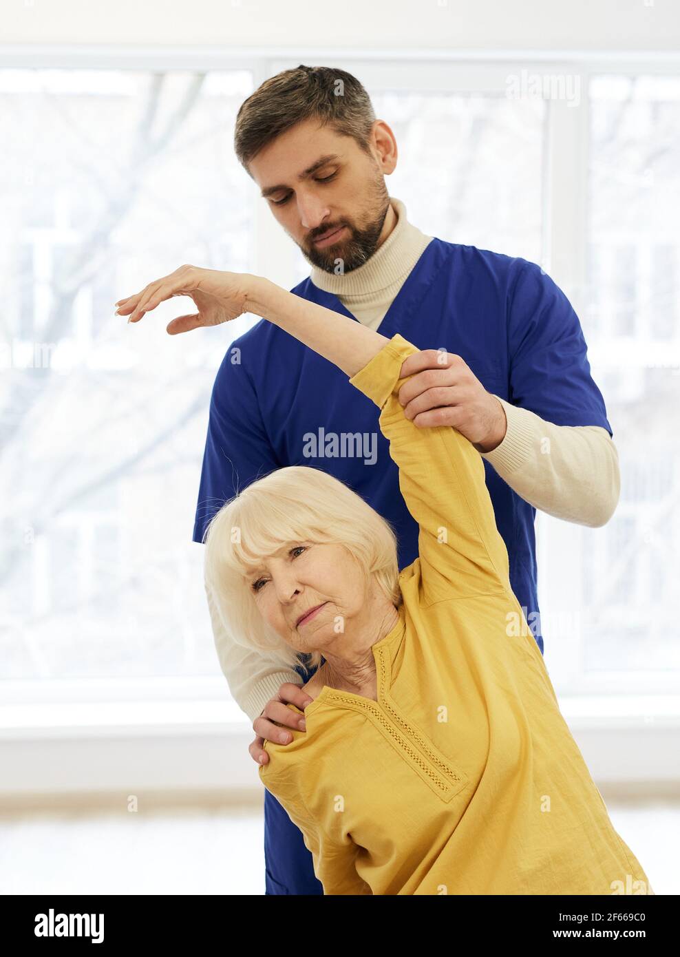 Paziente anziano durante il trattamento sotto sforzo con il suo fisioterapista esperto. Riabilitazione in un centro medico per anziani Foto Stock