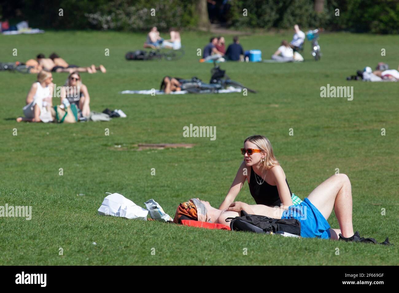 Londra, Regno Unito. Marzo 30 2021: Nel Parco di Dulwich il clima caldo e inestetonabile attira la gente fuori a prendere il sole, pic-nic, esercizio o semplicemente rilassarsi con gli amici o un buon libro. La riduzione del blocco da restrizioni del coronavirus ora significa che fino a 6 persone o due famiglie possono incontrarsi in giardini pubblici o privati. Credit: Anna Watson/Alamy Live News Foto Stock