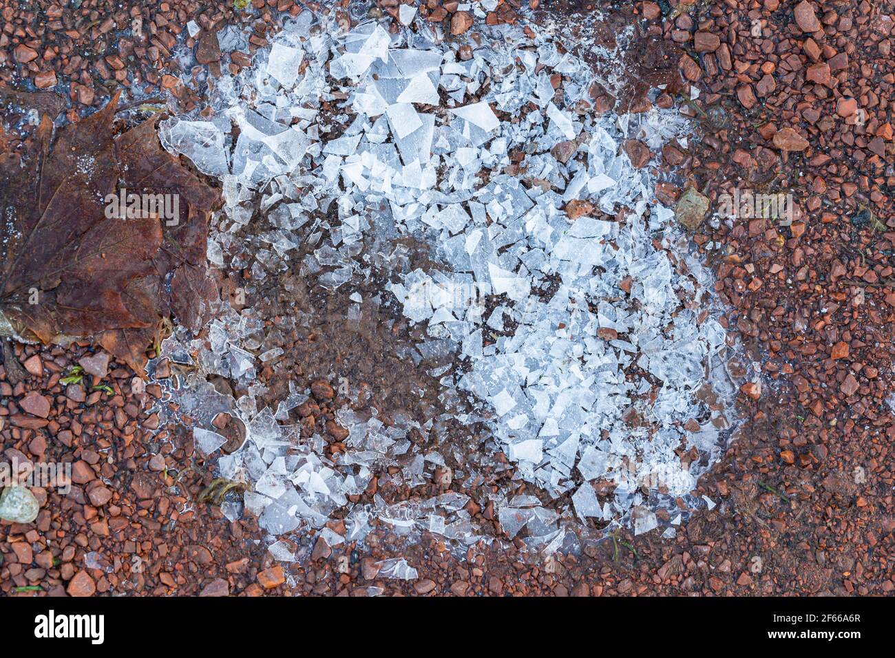 Ghiaccio bianco frantumato su ghiaia rossa Foto Stock