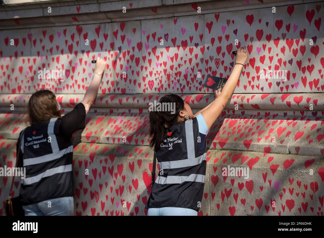 Londra, Regno Unito. 30 Marzo 2021. I volontari attirano il cuore su un muro a Lambeth, vicino al Tamigi, con ogni cuore che rappresenta qualcuno che è morto durante la pandemia di coronavirus in corso nel Regno Unito. Chiamato il National Covid Memorial Wall, è stato creato dalle famiglie covide-19 in lutto per la giustizia e si estende per mezzo miglio entro il momento in cui è completo. Credit: Stephen Chung/Alamy Live News Foto Stock