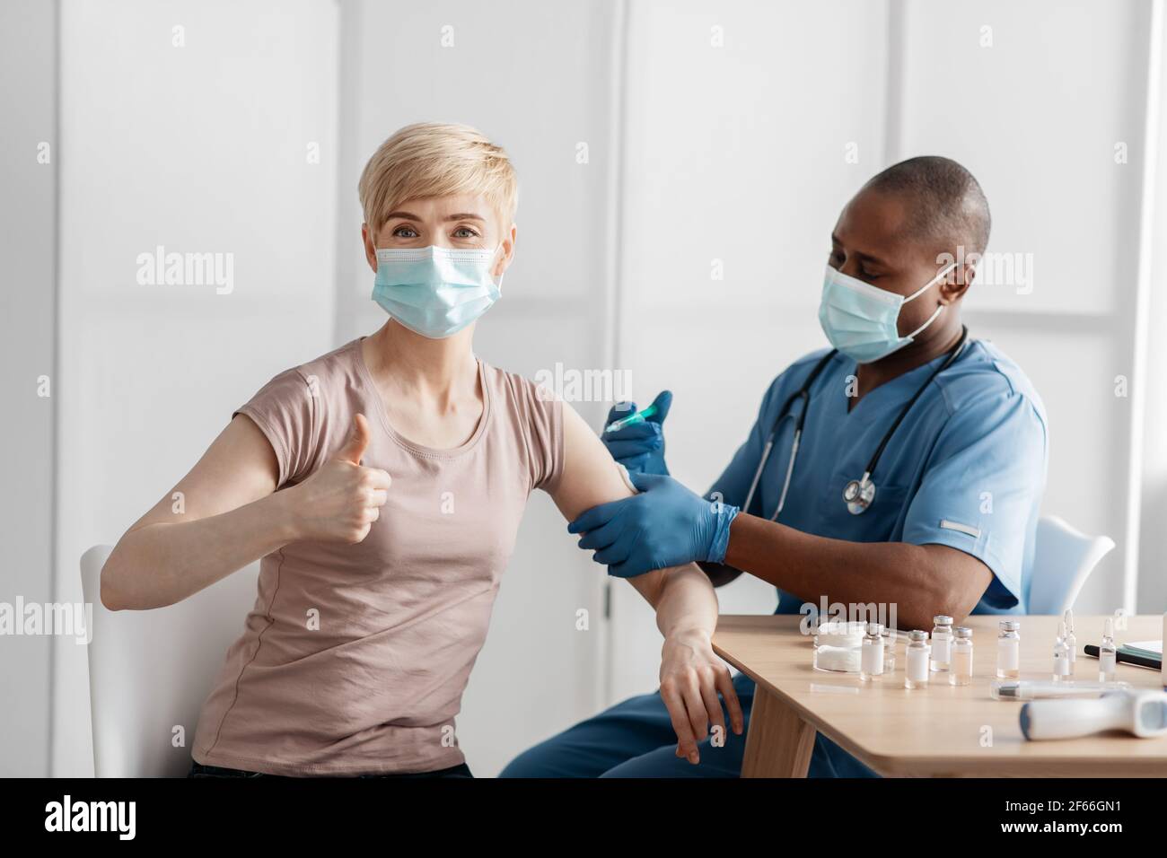 Medico in maschera protettiva iniettare il vaccino per stimolare l'immunità di paziente donna a rischio di coronavirus Foto Stock