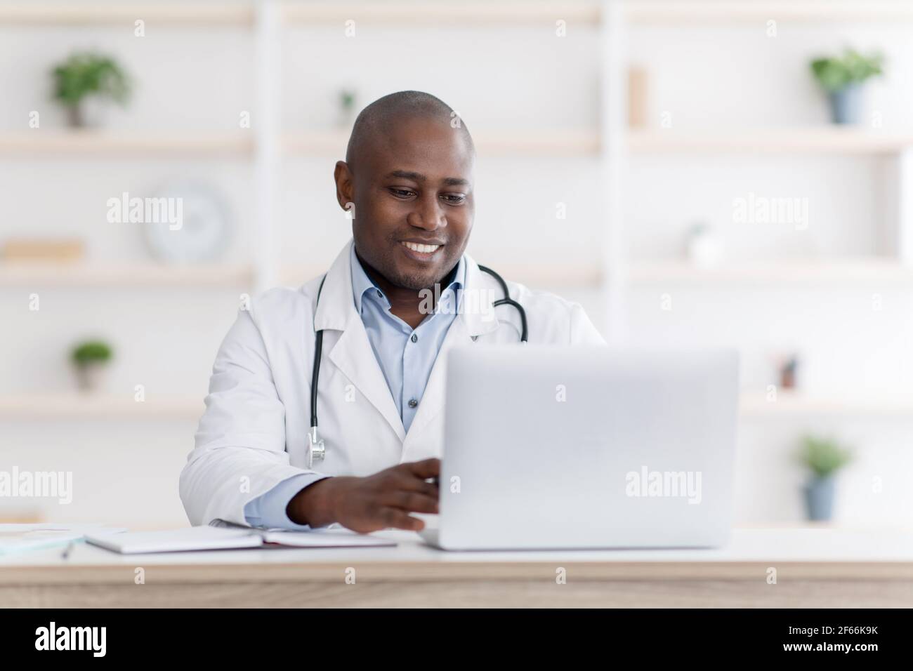 Consultazione medica online. Medico nero altamente qualificato che consulti i pazienti a distanza utilizzando un computer portatile Foto Stock