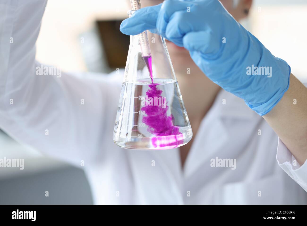 Chimico scienziato aggiungendo reagente al pallone di vetro con closeup dell'acqua Foto Stock