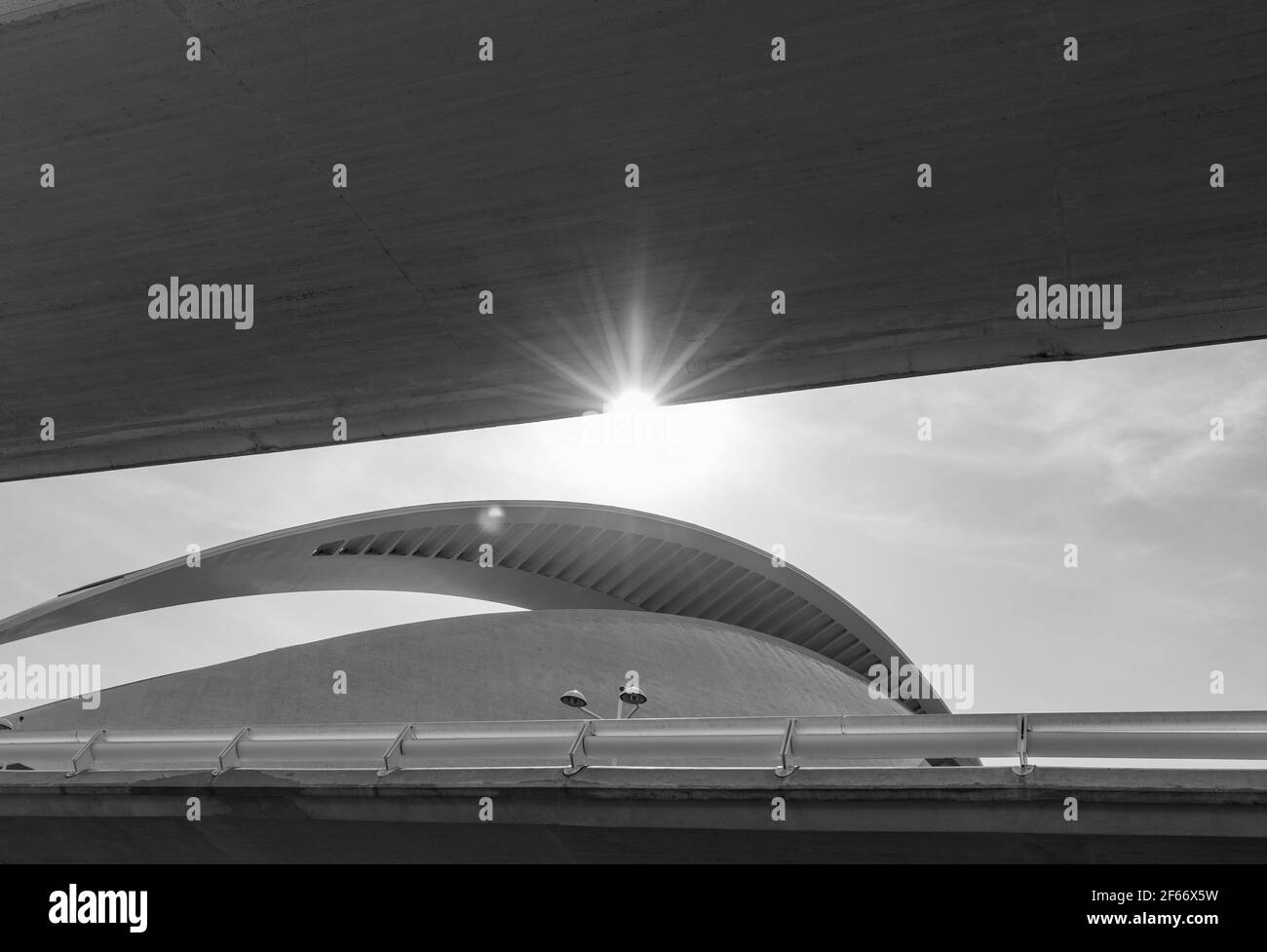 Valencia - Spagna. 24 giugno 2019: Un bagliore di sole incornicia il tetto curvo del teatro lirico tra i ponti, fotografato in bianco e nero. Foto Stock