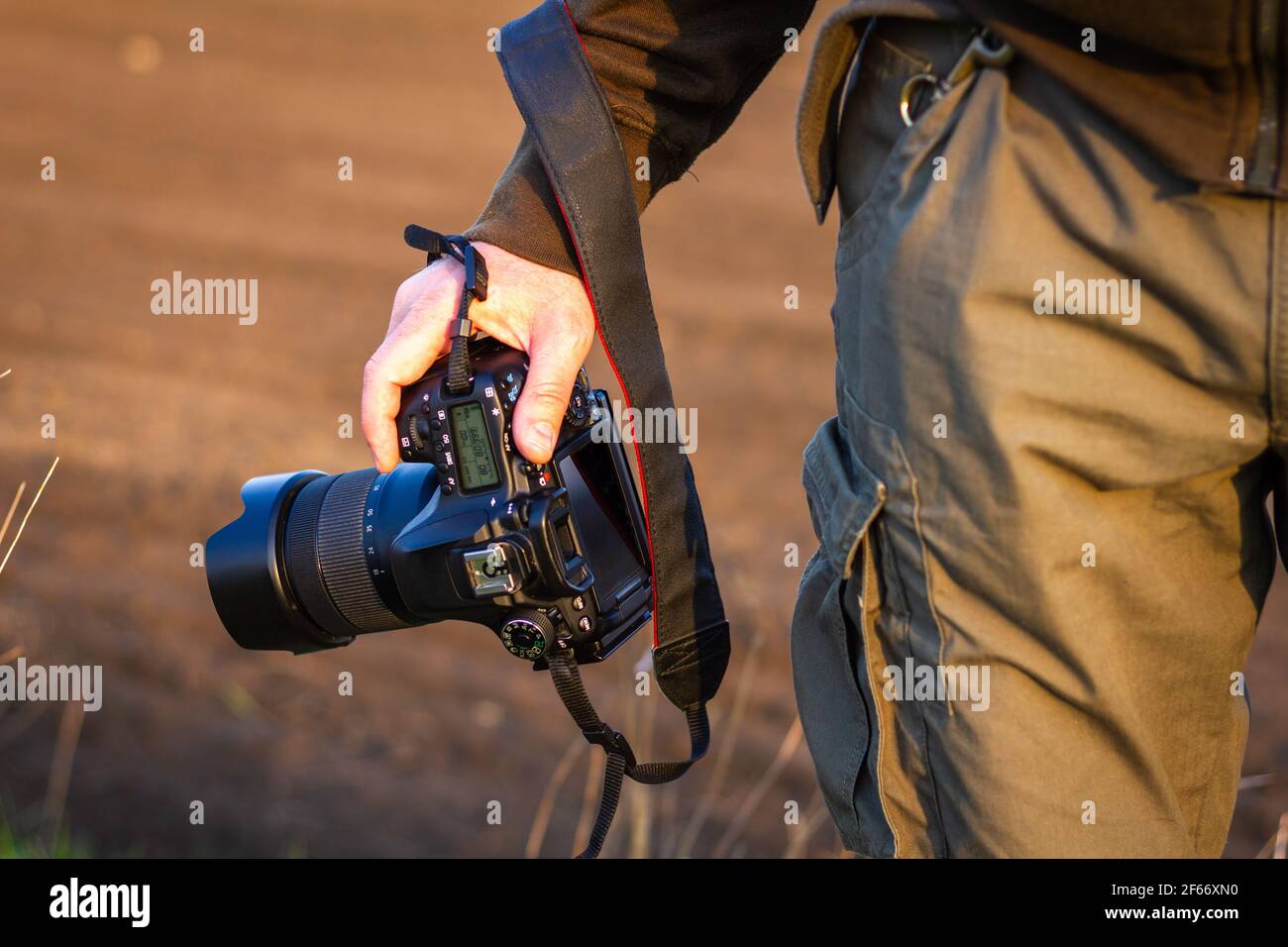 Fotocamera in mano. Fotografo che tiene la fotocamera digitale all'aperto. Avventura nella natura Foto Stock