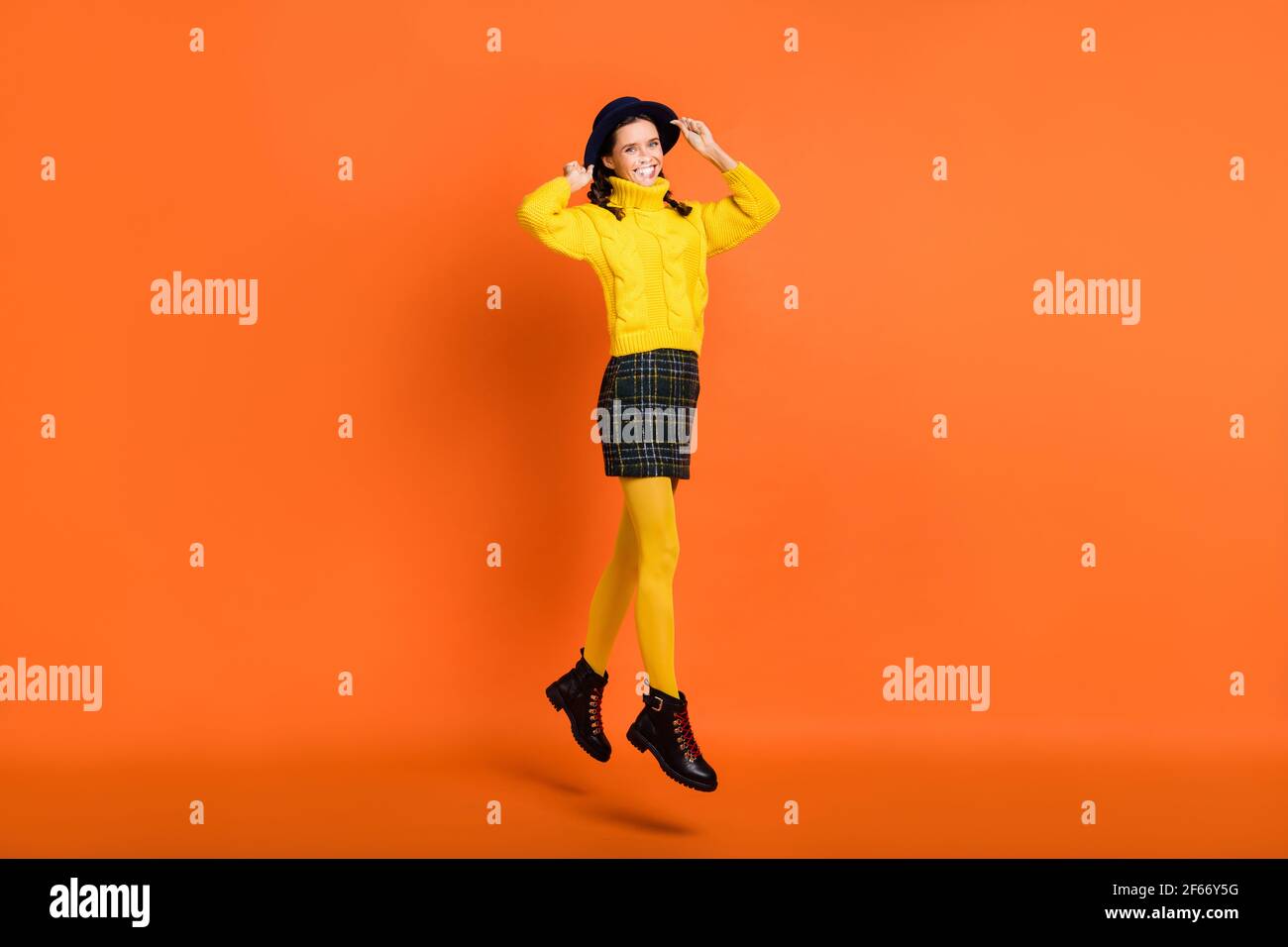 Vista a tutta lunghezza del corpo di bella pelle carina felice ragazza allegra saltando isolato su sfondo di colore arancione brillante Foto Stock