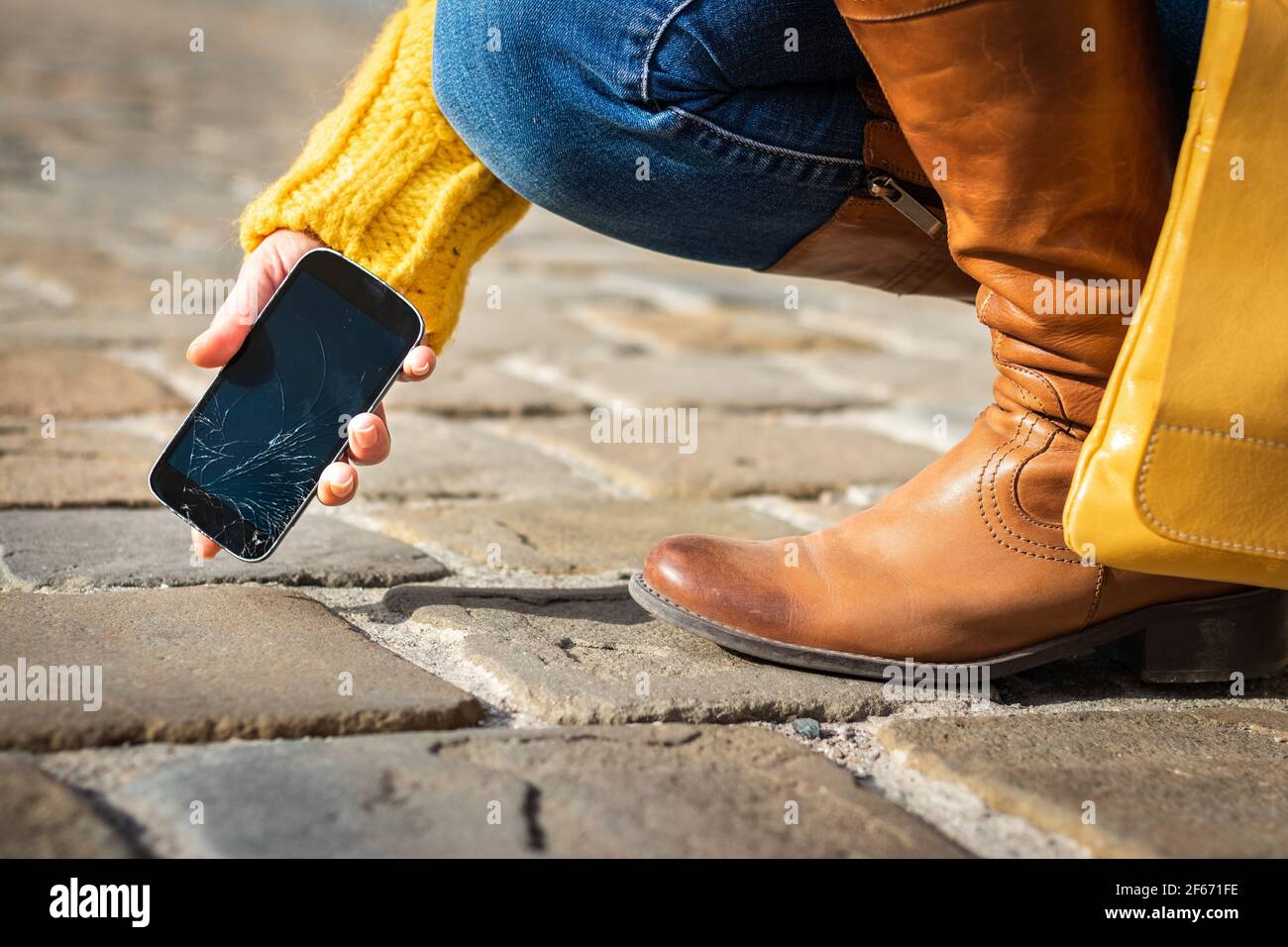 Donna che raccoglie smartphone danneggiato con schermo a sfioramento rotto sulla strada. Telefono cellulare rotto. Foto Stock