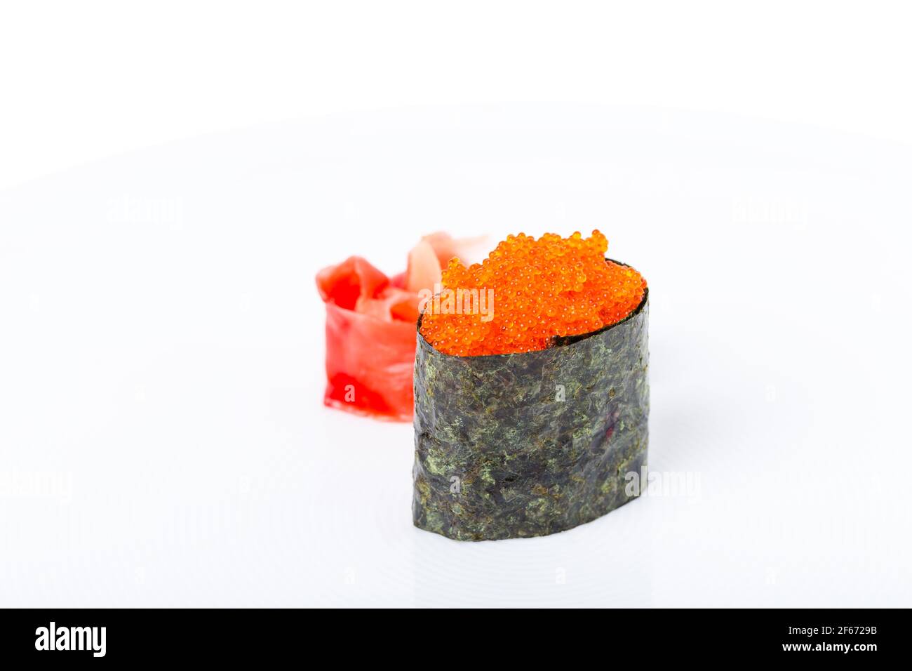 Sushi Gunkan farcito con caviale tobiko rosso. Servito con un mucchio di zenzero e wasabi. Macro. Può essere utilizzato come sfondo completo. Foto Stock