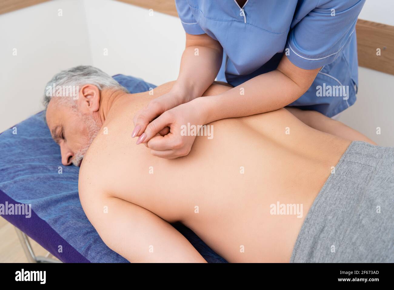massaggiatrice che fa massaggio alla schiena per l'uomo maturo sdraiato sul massaggio tabella Foto Stock