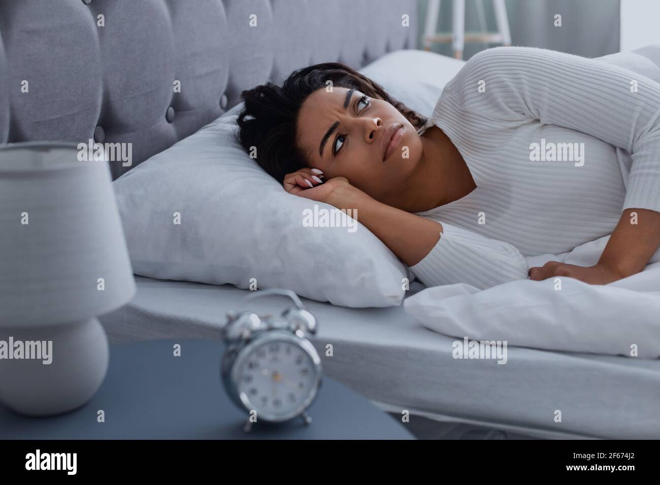 Donna nera che soffre di insonnia guardando il soffitto Foto Stock