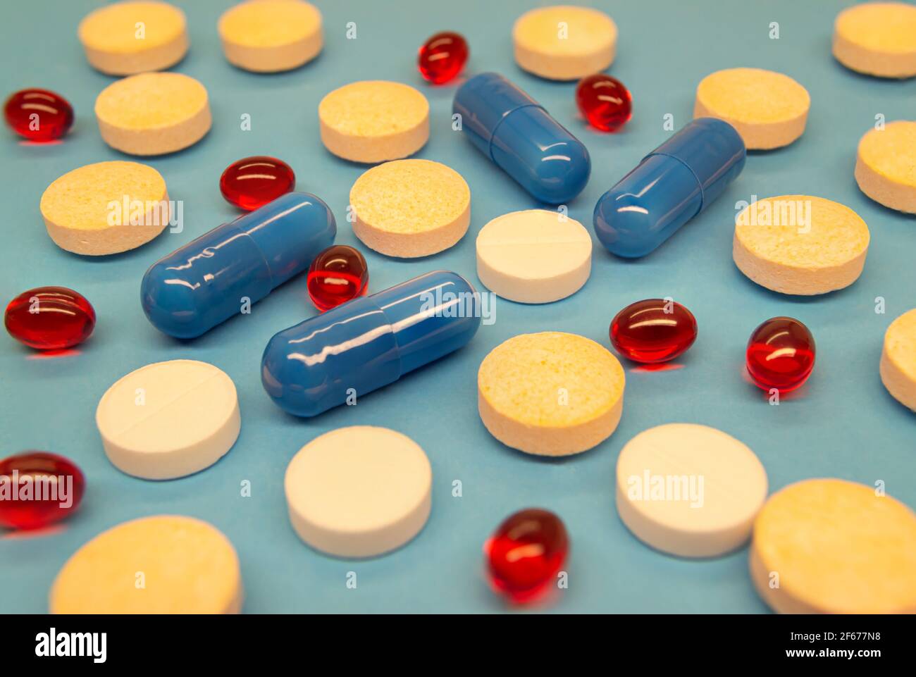 Pillole multicolore miste riempiono l'intera immagine su uno sfondo blu. Assistenza sanitaria. Immagine della medicina Foto Stock