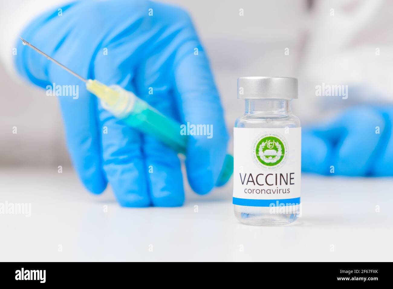 Accademia cinese di scienze mediche vaccino contro il coronavirus e siringa per l'iniezione in mano operatore sanitario in guanti di gomma e. tuta protettiva Foto Stock