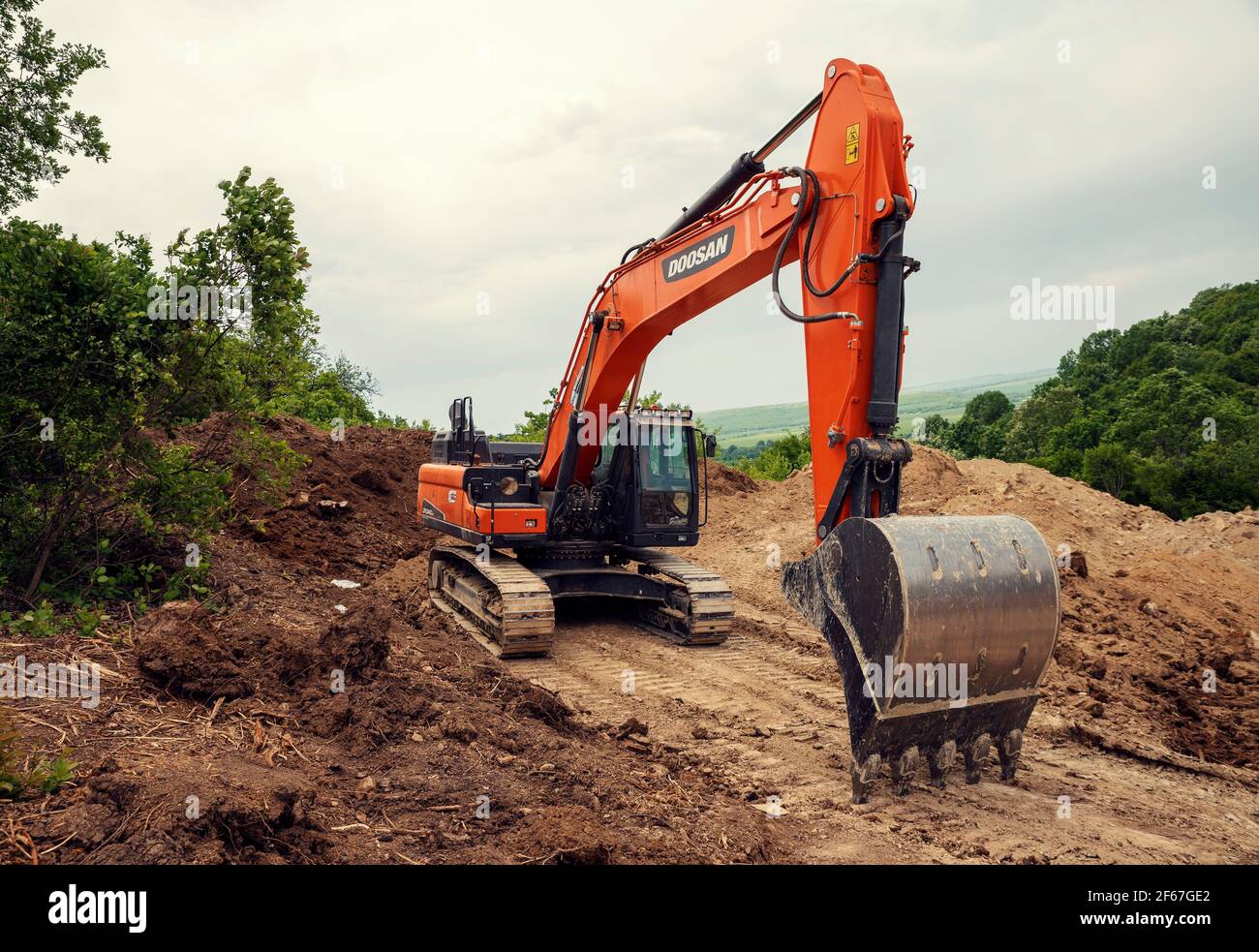 Bulgaria, Radanovo, 20 MAGGIO 2020: Un escavatore a catena arancione che sgombrano il terreno su un pendio durante la costruzione del gasdotto South Stream Foto Stock