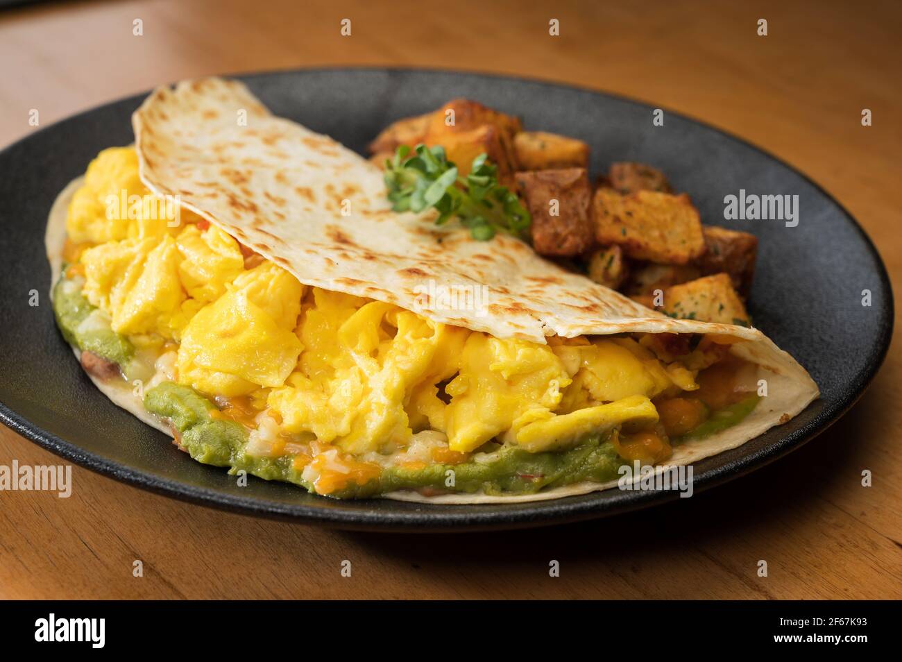 Huevos Rancheros. Tre uova strapazzate in tortilla di farina con fagioli, guacamole e formaggio grattugiato. Foto Stock