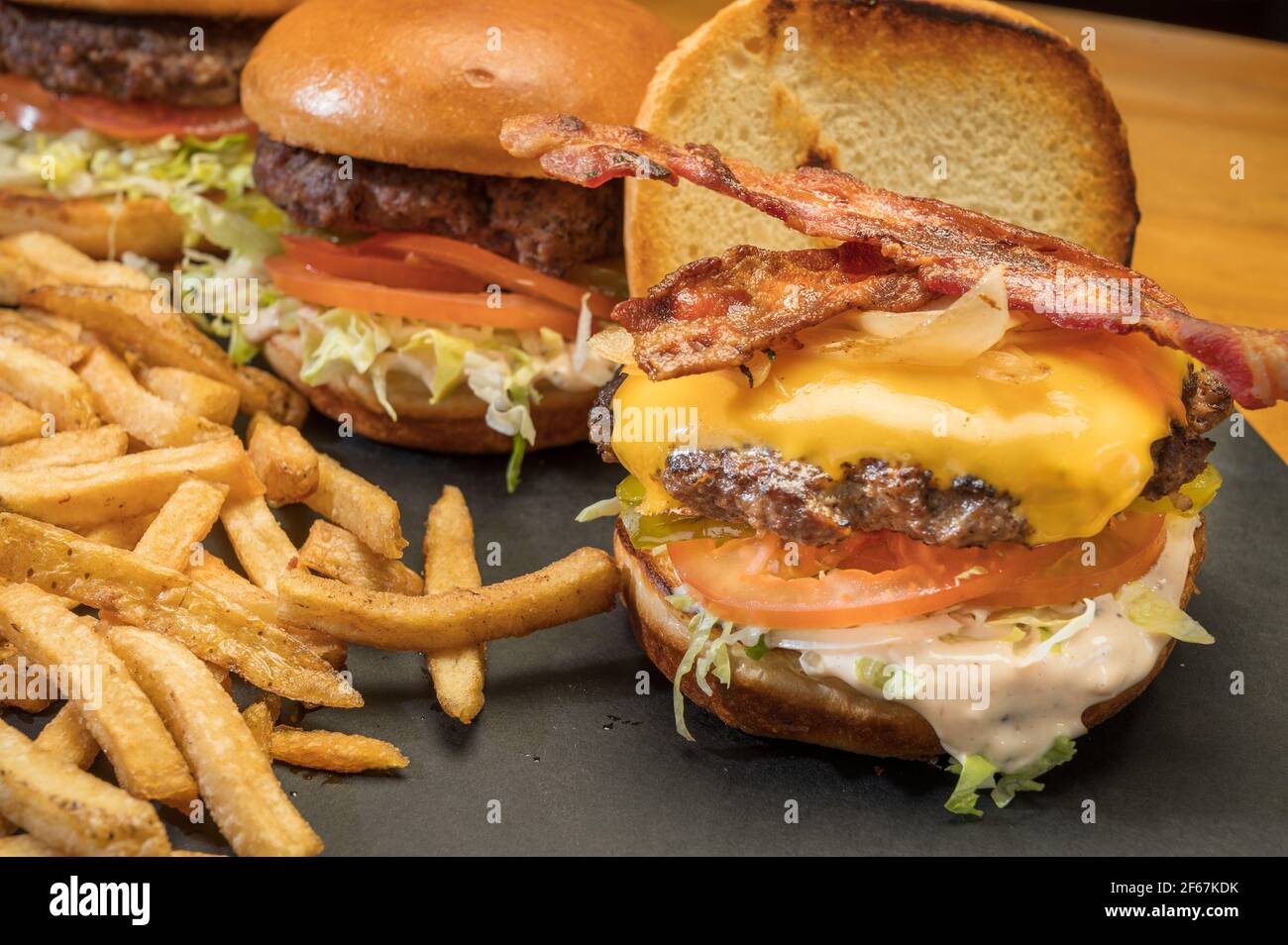 Piatto di hamburger con formaggio bacon e patatine fritte in un ristorante in stile cena. Foto Stock