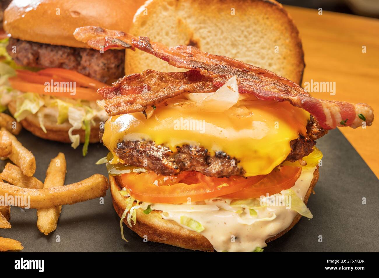 Piatto di hamburger con formaggio bacon e patatine fritte in un ristorante in stile cena. Foto Stock