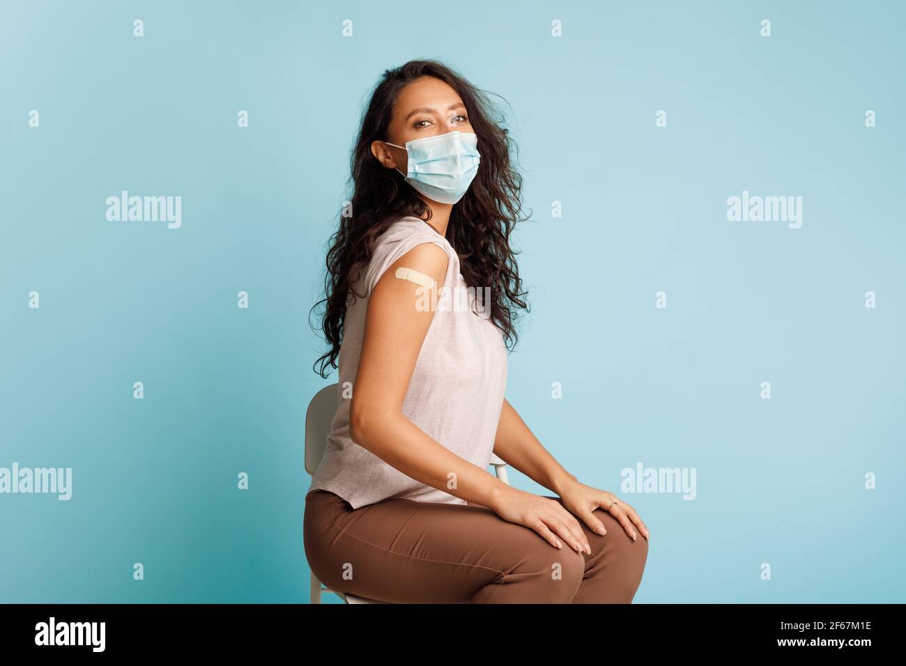 Donna vaccinata contro Covid-19 che mostra braccio dopo l'iniezione del vaccino, studio Foto Stock