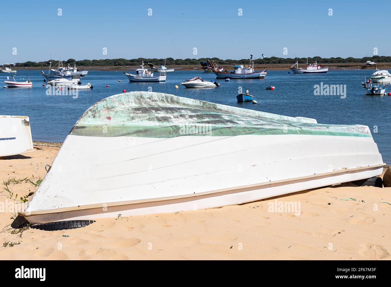 La barca da pesca riposa sulla spiaggia di sabbia che si affaccia sul mare blu a Punta Umbria, Huelva, Andalusia, Spagna Foto Stock