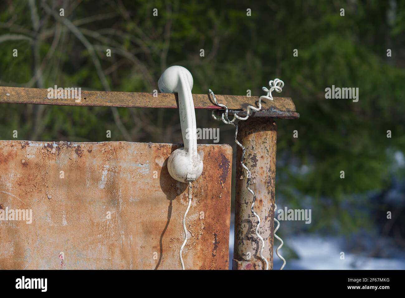 Vecchio telefono abbandonato appeso nella recinzione, closeup all'aperto Foto Stock
