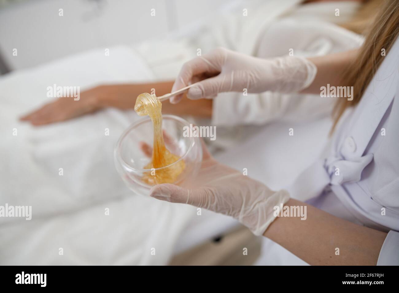 Zuccheratura con materiali naturali. Il medico mette cera, miele. Concetto di medicina, strumenti medici, assistenza sanitaria, industria di bellezza, rimozione dei capelli Foto Stock